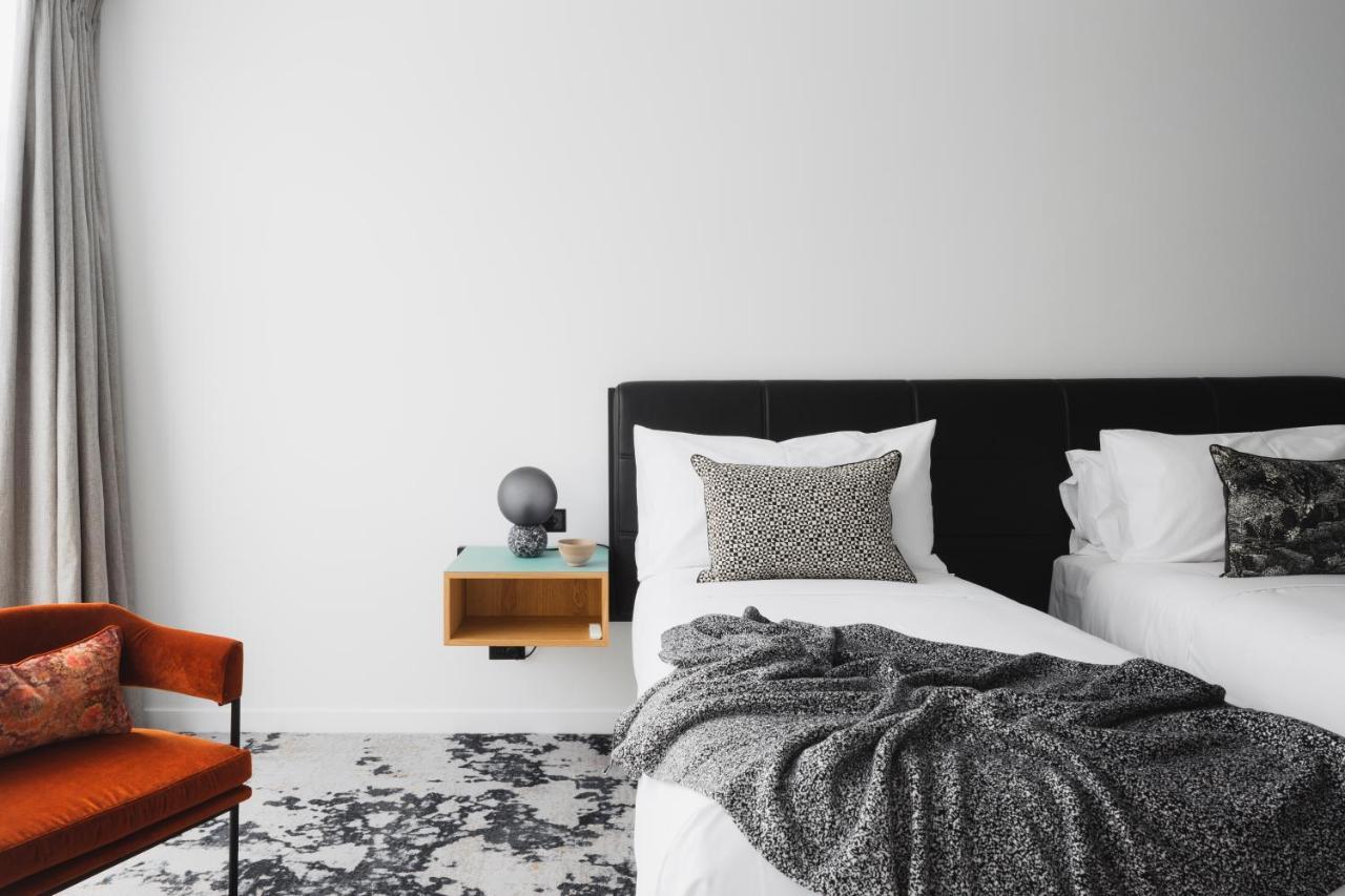 Ebb-Dunedin Esterno foto A bedroom with a bed, a chair and a nightstand